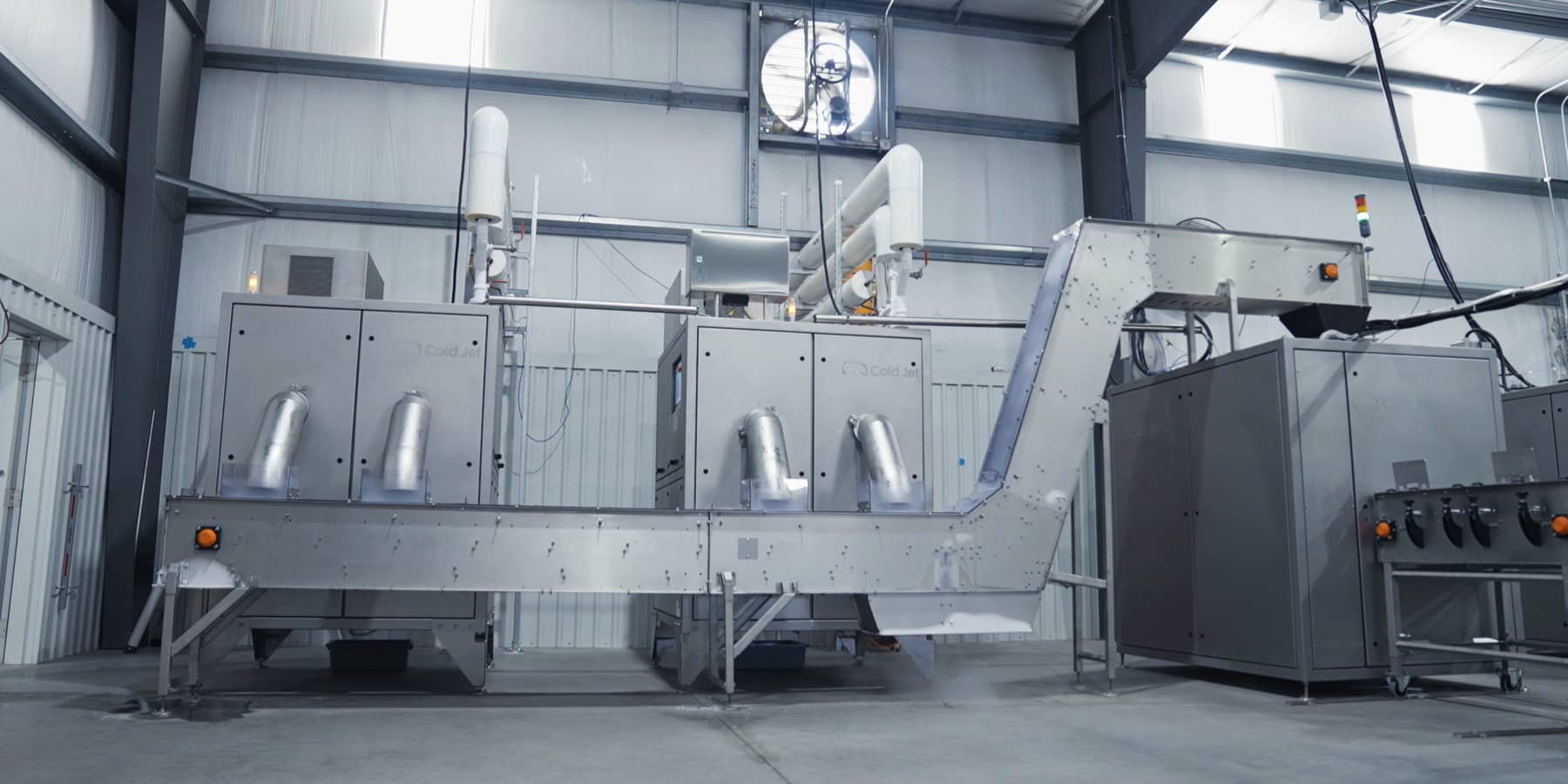 Ein silberner, industrieller Reformer mit Rohren und einer Rampe in einer Lagerhalle.