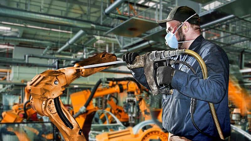 worker using dry ice blasting machine to clean robotic arm